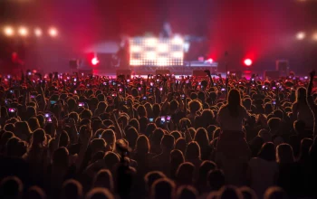 A crowd of people with their hands in the air or filming with their phones at a concert.
