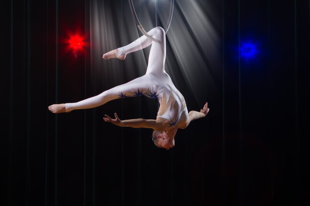 A trapeze artist preforming at a circus.