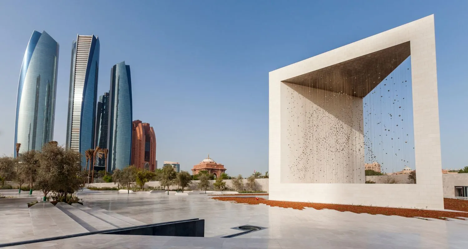 The Founder's Memorial's open white pavilion by day, with the Etihad Towers rising behind it in Abu Dhabi