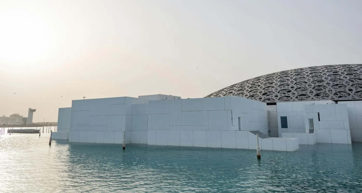 Louvre Abu Dhabi surrounded by turquoise water and modern white architecture