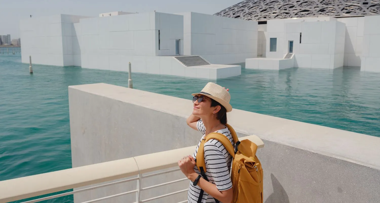 Traveler exploring the waterfront outside Louvre Abu Dhabi on a sunny day