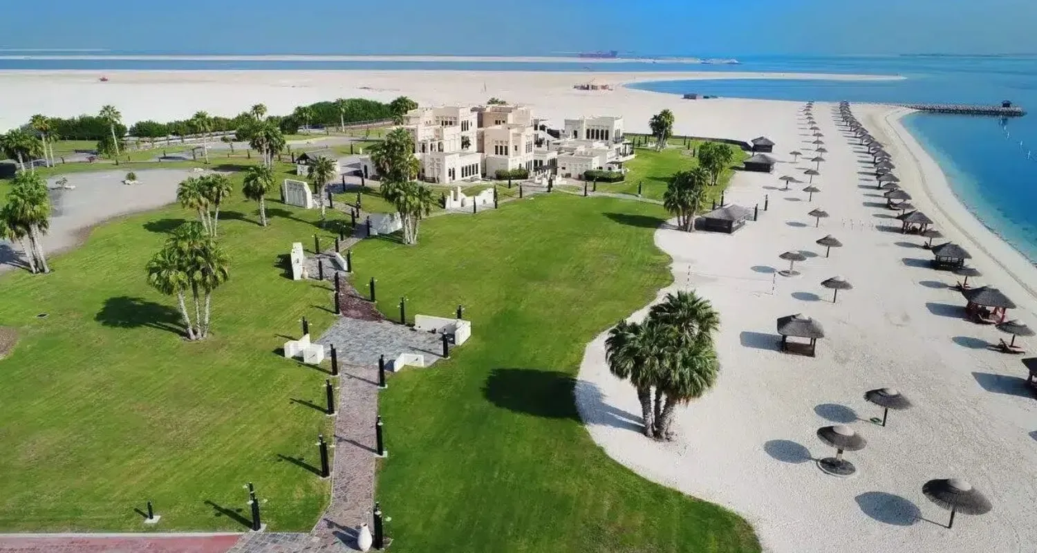 Aerial shot of beach villas, lawns, and shaded cabanas at Al Maya Island & Resort