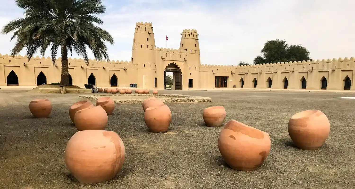 Al Jahili Fort's mud-brick towers rising behind rows of clay pots in Al Ain