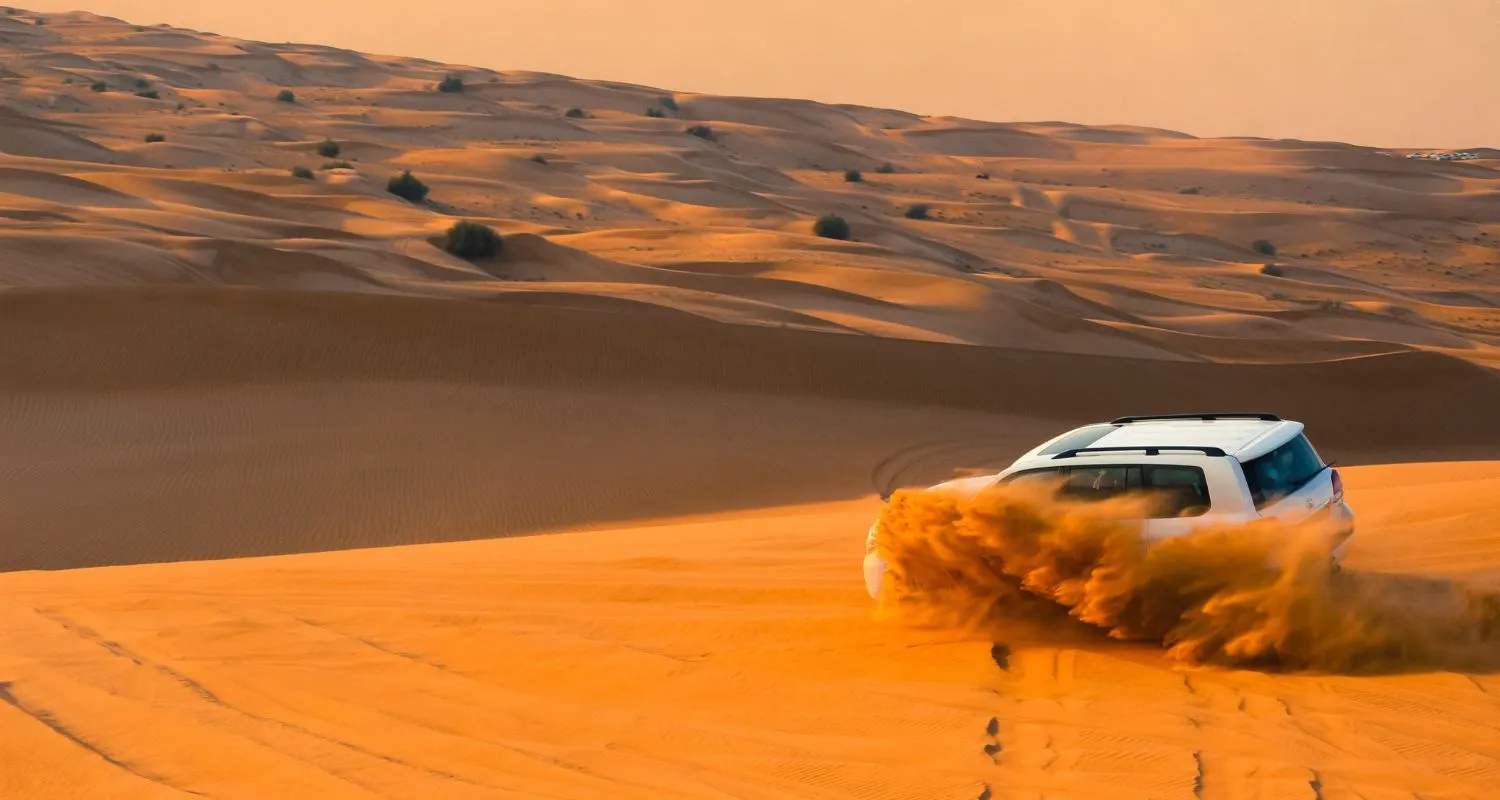 White 4x4 kicking up sand while dune bashing on a Liwa desert safari