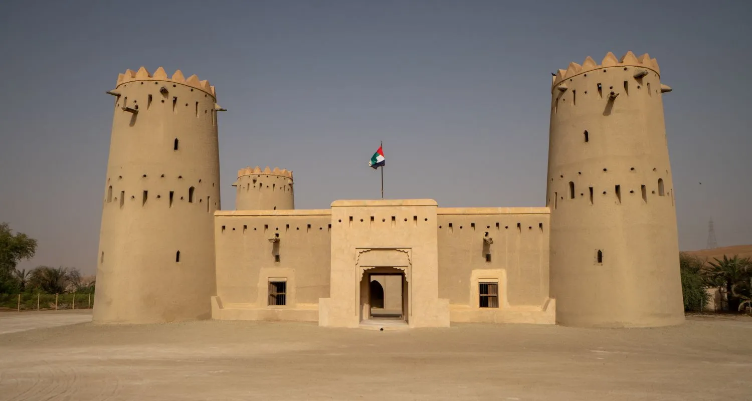Restored mud-brick fort with two watchtowers and the UAE flag in Liwa Oasis